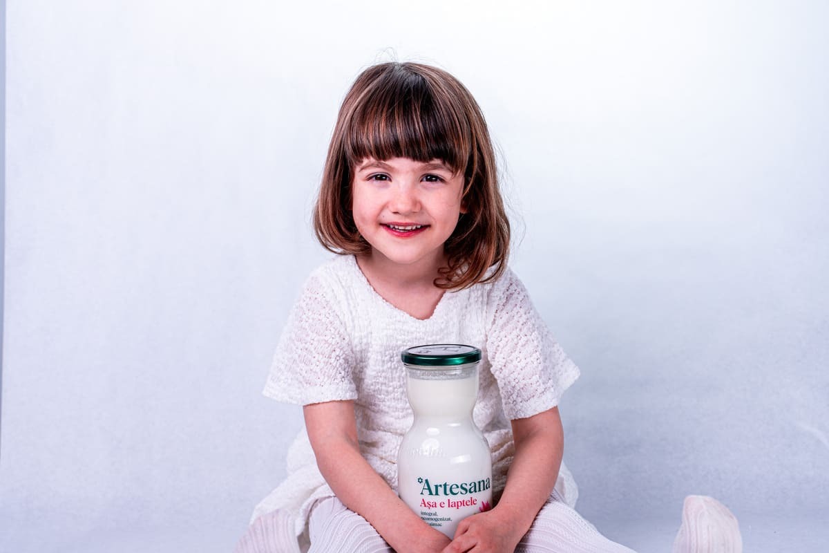 copil care tine in brate o sticla de lapte Artesana